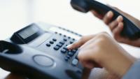 woman's hand dialing on a landline phone